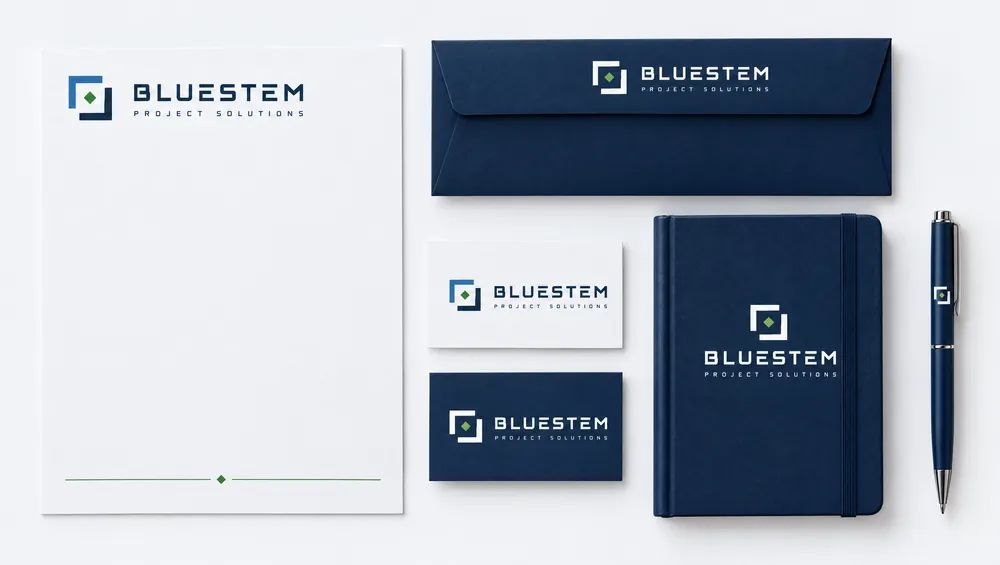 A stationery set on white: a letterhead with a thin green line and diamond at the foot, a navy envelope, two business cards, a navy notebook and a pen, all carrying the Bluestem logo.