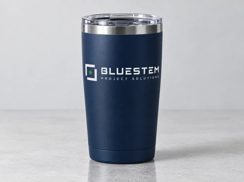 A navy insulated tumbler with a clear lid and the Bluestem logo printed in white with a green diamond.
